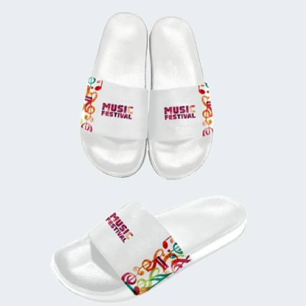 A pair of white slides featuring a vibrant patterned strap with a logo. The slides have a glossy finish.