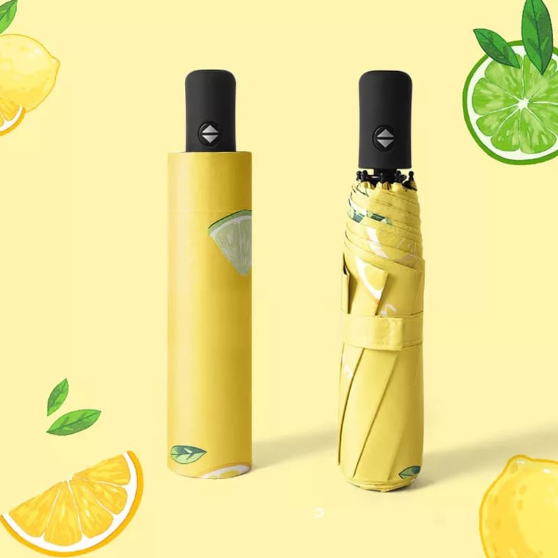 A yellow umbrella with a lemon and lime design, featuring a black handle and a matching storage sleeve.
