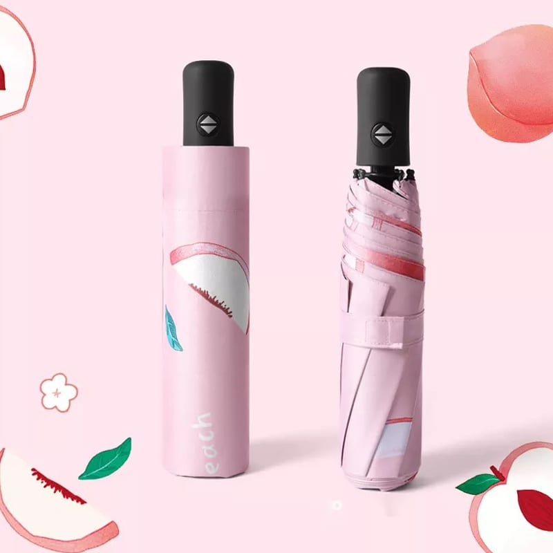 A pink umbrella with a peach design, featuring a compact case and a black handle. It has a logo.