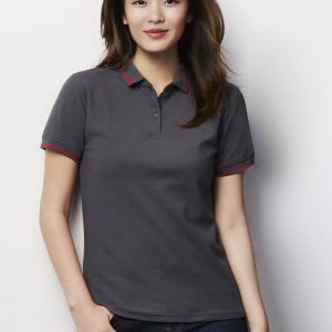 A women’s short sleeve polo in charcoal grey with red accents, featuring a collar and a logo.