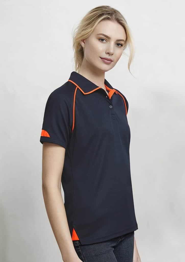 A navy blue women's polo shirt featuring orange accents on the collar and sleeves, with branding.