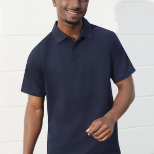 A navy short sleeve polo shirt with a collar and a logo, worn by a smiling man against a white wall.