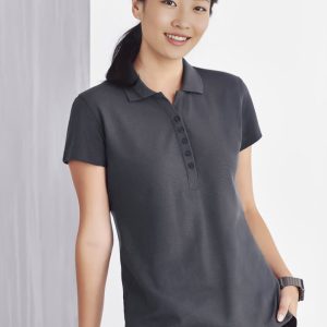 A dark grey polo shirt for ladies, featuring a collar and button placket, displayed on a smiling model.