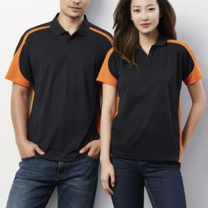 A black polo shirt with orange accents, featuring a logo, modelled by a man and a woman against a white background.