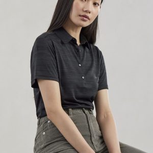 A women's short sleeve polo shirt in a dark colour featuring a subtle textured pattern and buttons, paired with beige trousers.
