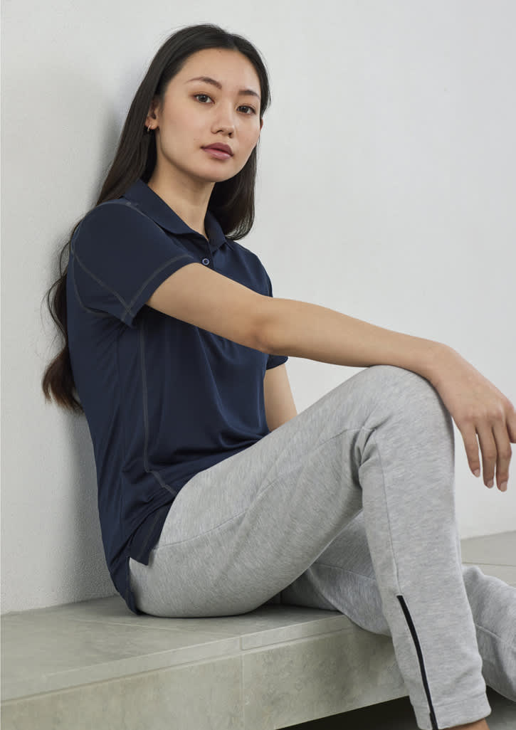 A women's short sleeve polo shirt in navy blue, paired with grey pants, displayed against a plain background.