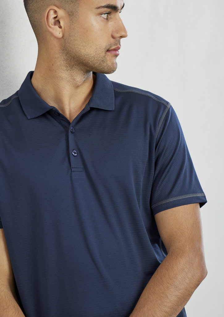 A navy blue short sleeve polo shirt with a collar, featuring a logo on it. The model is looking to the side.