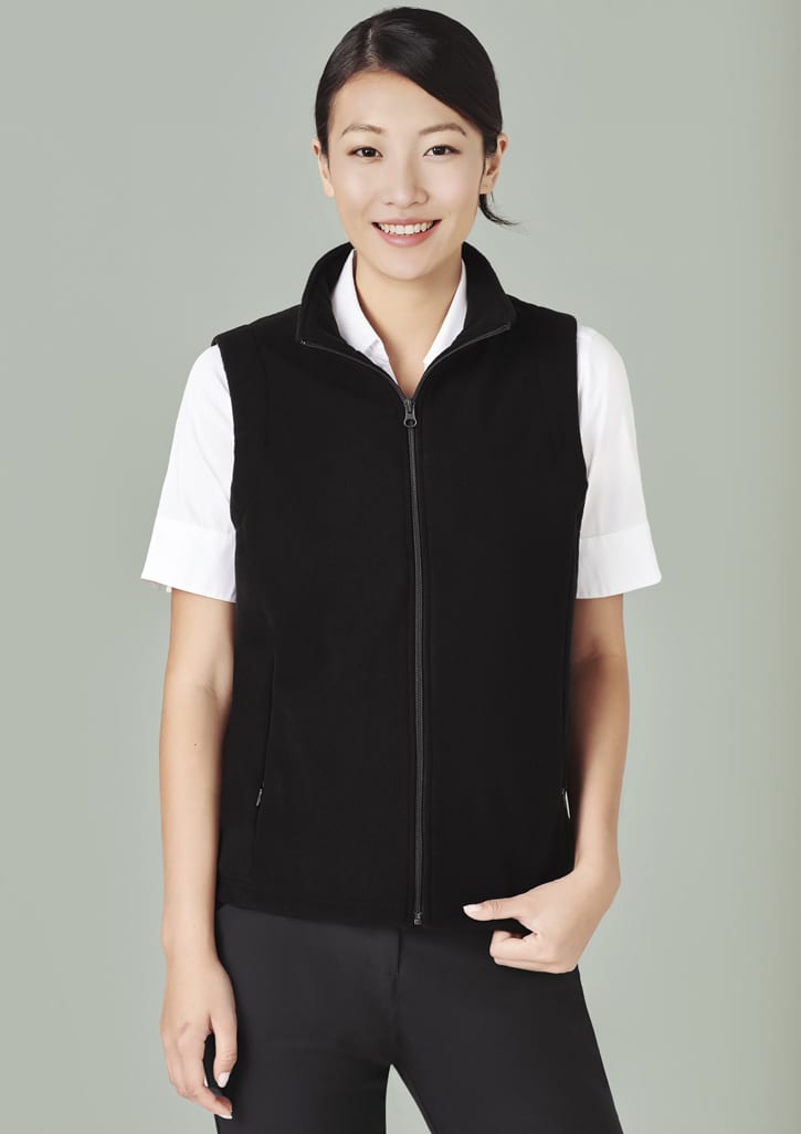 A black micro fleece vest with a zip, worn over a white shirt, featuring side pockets and a neckline zip.