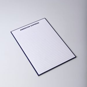 A5 note pad in navy blue with lined pages and a logo in the corner. Contains 50 leaves.