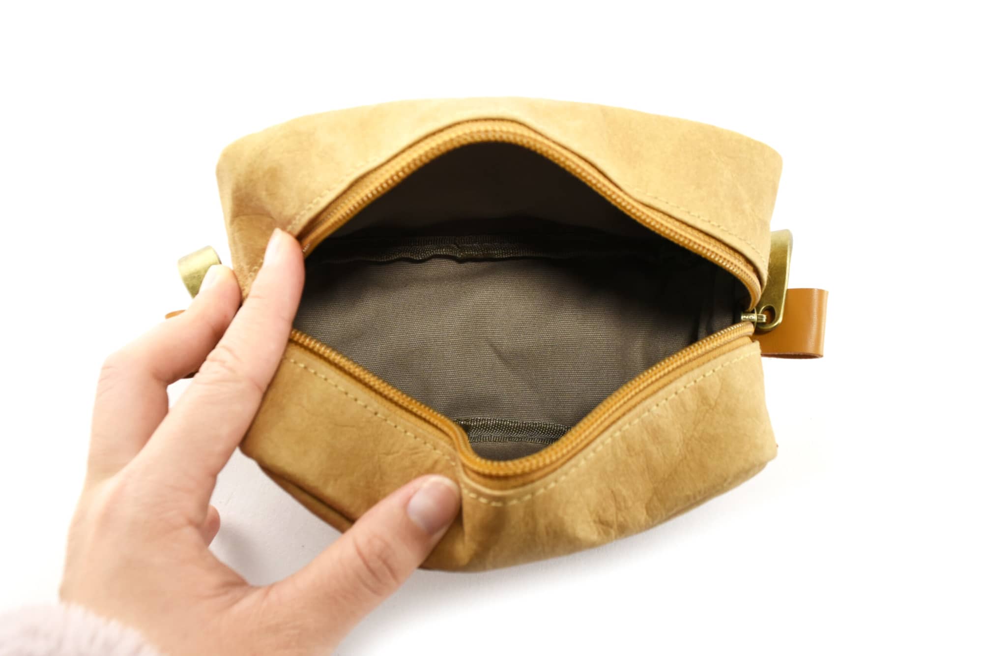A tan kraft paper cosmetic bag with a zipper and a leather-like tab, featuring a plain interior lining.