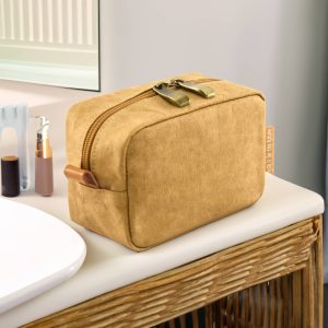 A tan kraft paper cosmetic bag with a zipped closure, resting on a bathroom countertop near toiletries.