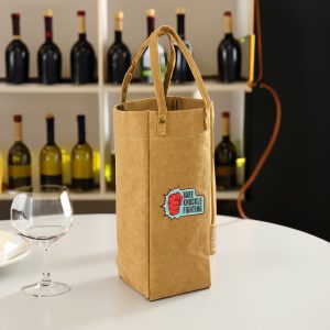 A Kraft paper wine carry bag in brown with handles and a logo, set against a backdrop of wine bottles.