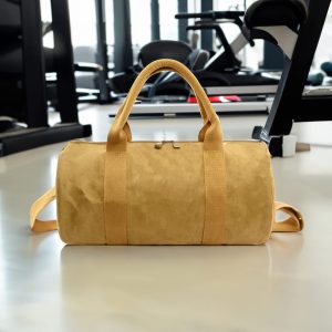 A yellow Manila Kraft paper duffle bag with handles and a shoulder strap, displayed in a gym setting.