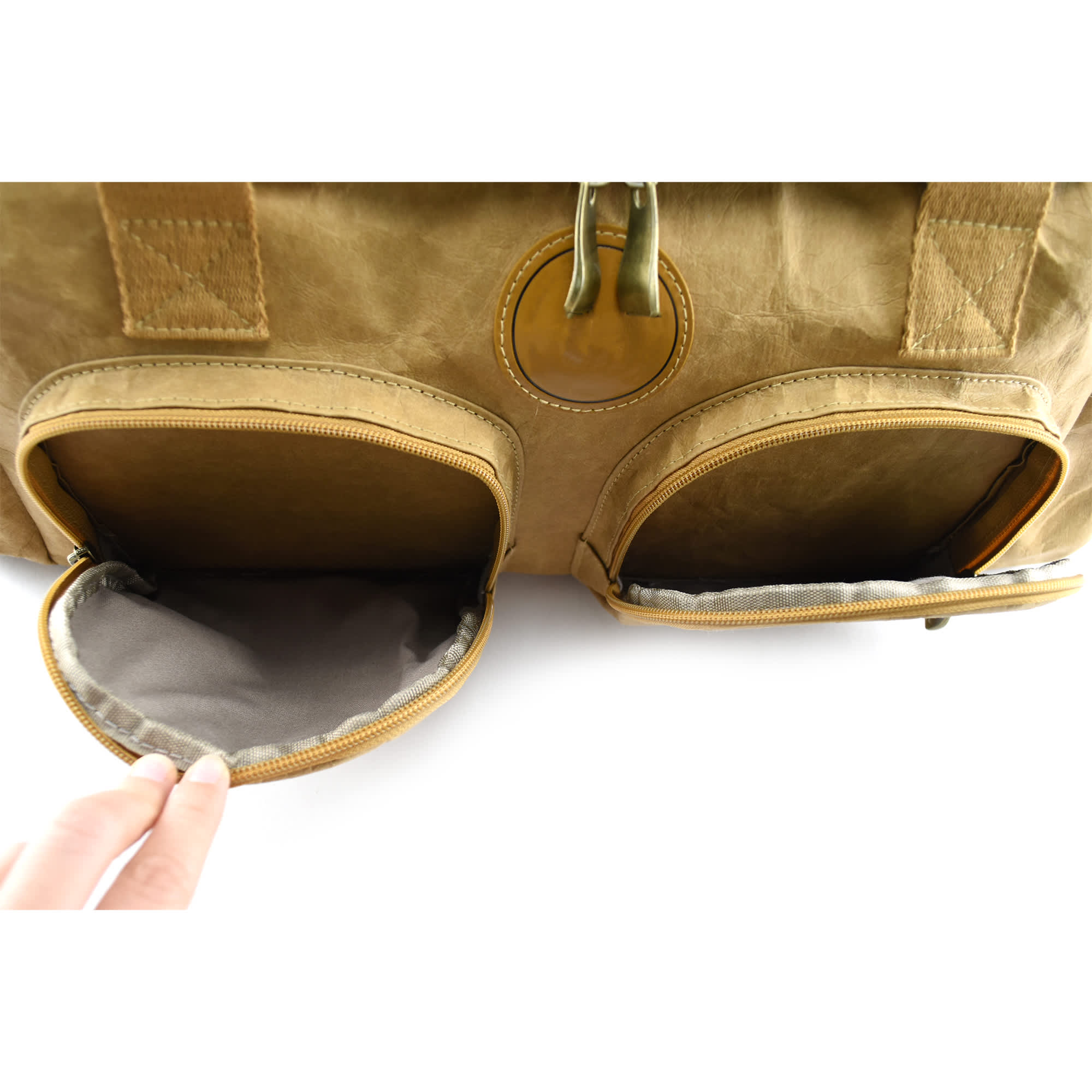 A brown Kraft paper duffle bag featuring two zippered pockets and sturdy handles. The bag has a simple logo.