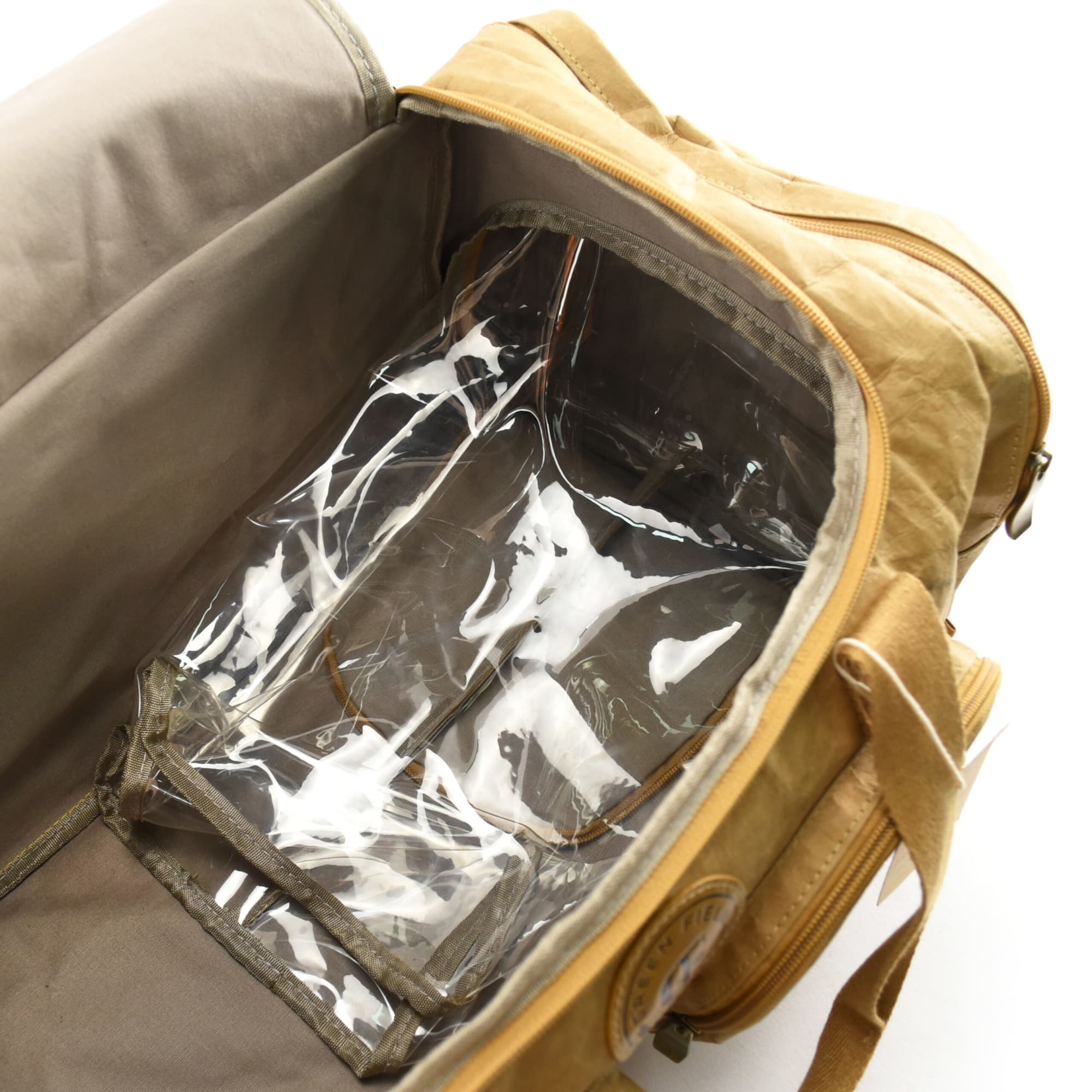 A tan duffle bag with a clear interior compartment and sturdy handles, featuring a logo.