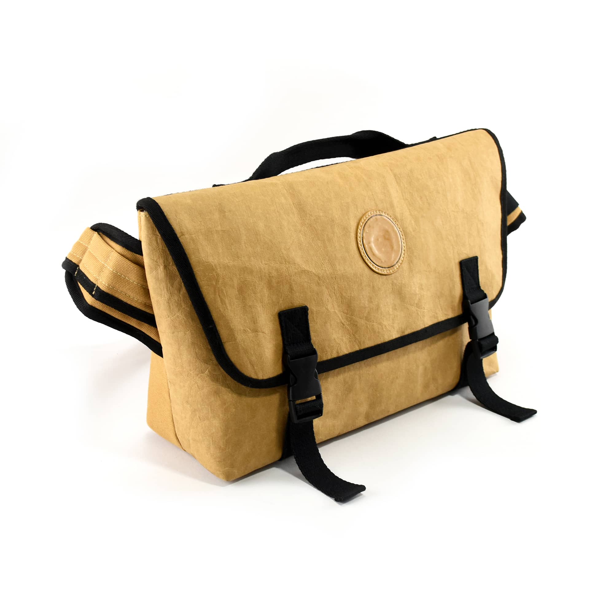 A kraft paper laptop messenger bag in beige with black straps, featuring a circular logo on the front.