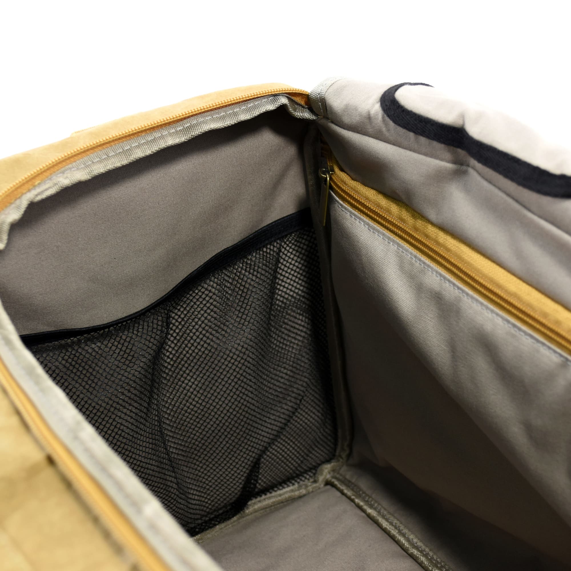 An interior view of a tan kraft paper duffle bag featuring a zippered pocket and a mesh compartment.