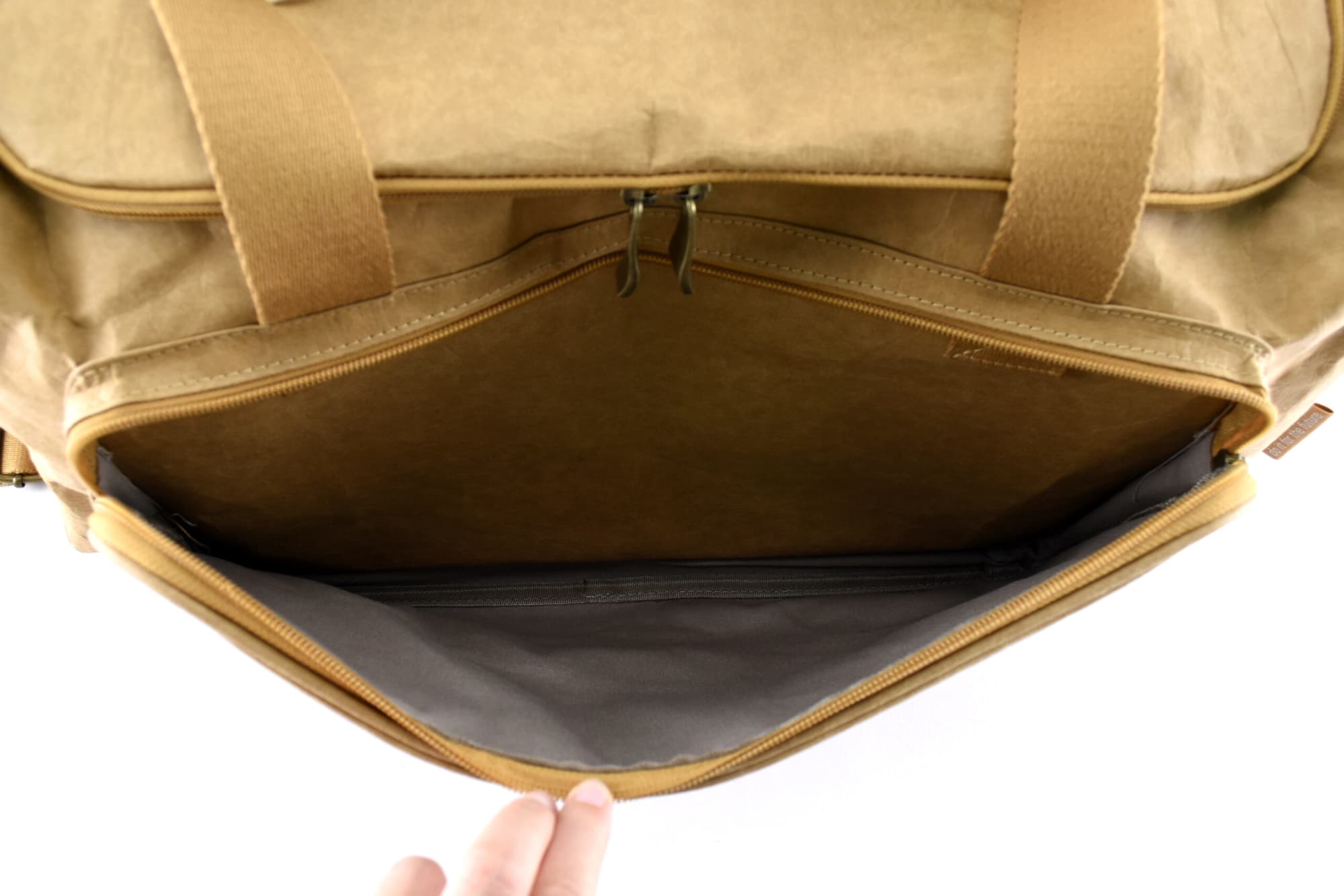 A tan kraft paper duffle bag with a spacious interior and a zippered compartment, showcasing its inside design.