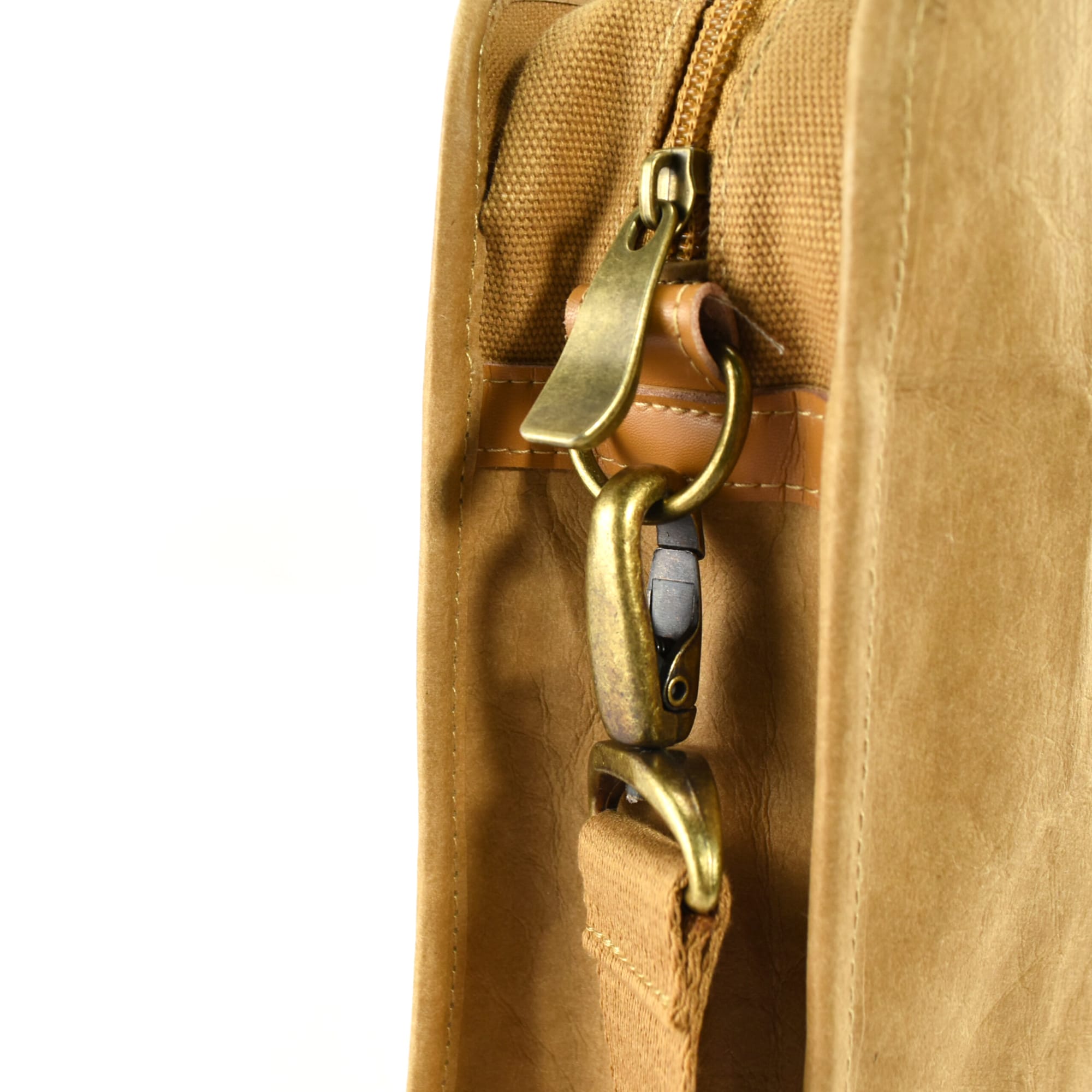 A tan satchel with brass hardware and a zip closure. It features a shoulder strap attachment point.