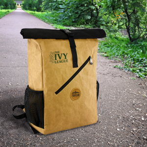 A kraft paper laptop backpack in tan with a black flap, featuring a front zip pocket and side mesh pockets.