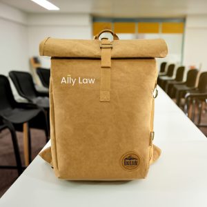A tan kraft paper laptop backpack with a roll-top design and a logo on the front.
