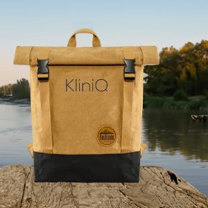 A khaki and black laptop backpack with adjustable straps and a logo on the front, set against a natural landscape.