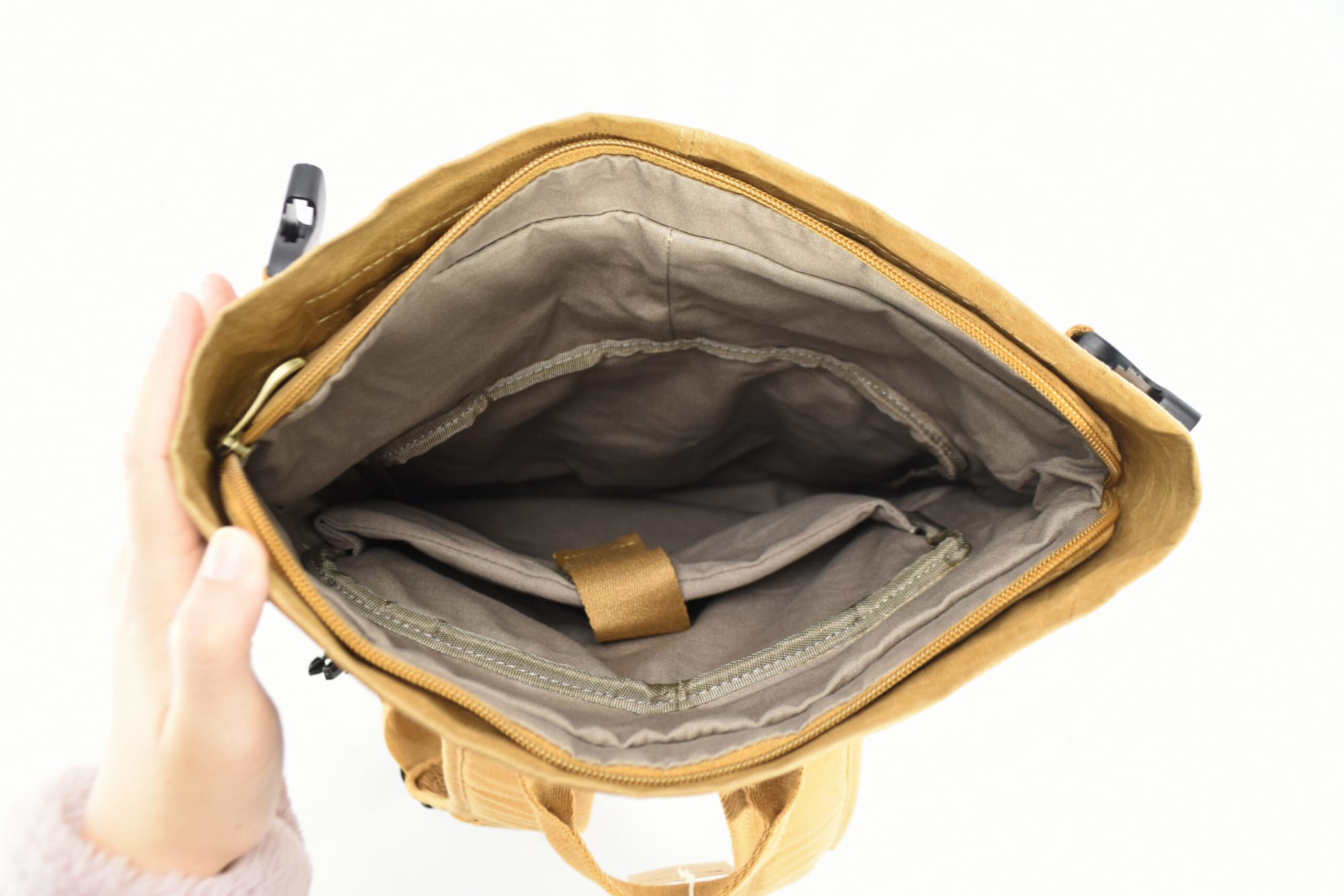 A laptop backpack in tan with a spacious interior, featuring multiple compartments and a grey lining.