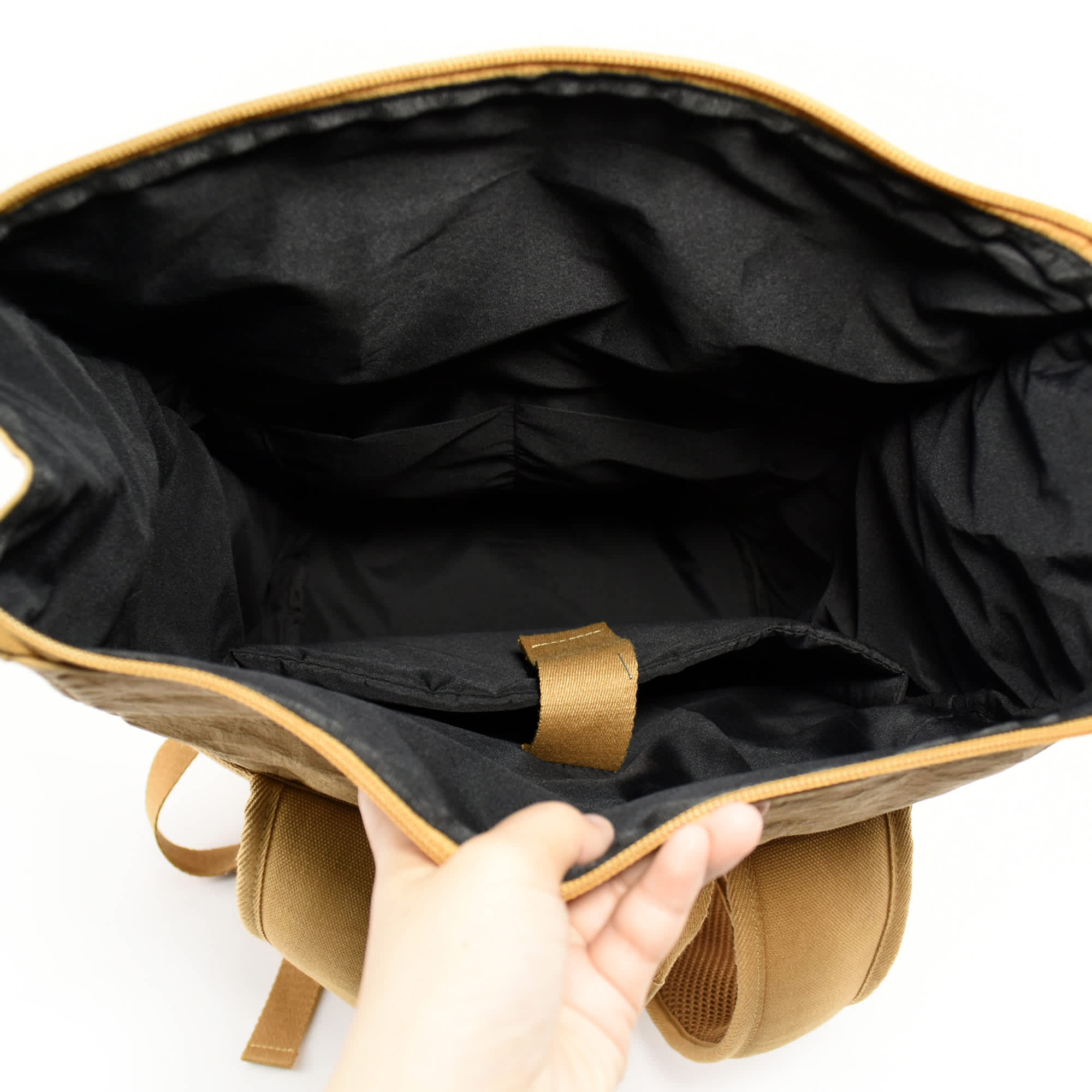 A laptop backpack with a kraft paper exterior and a spacious black interior, featuring compartments and a branding logo.