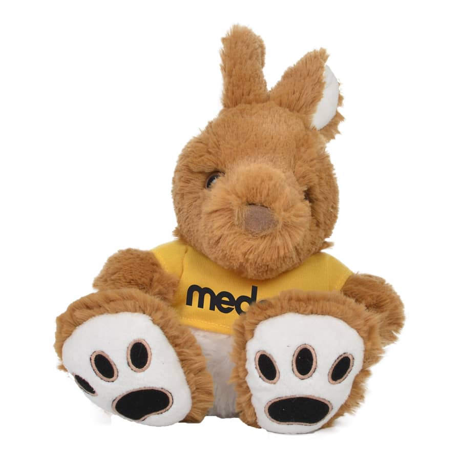 A plush kangaroo toy in brown with white paws, wearing a yellow shirt and featuring a logo on it.