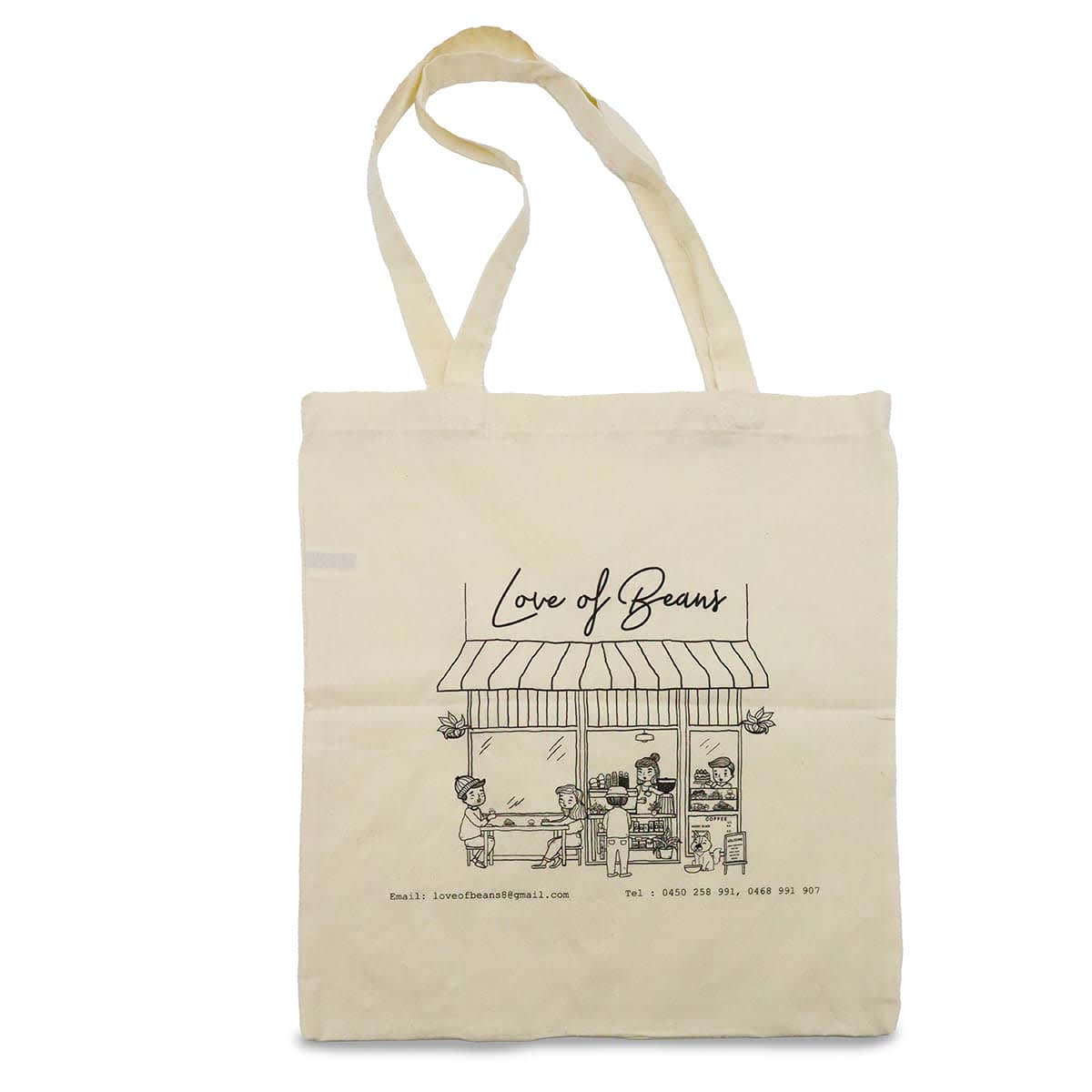 A cream-coloured calico tote bag featuring an illustration of a coffee shop and a logo. It has long handles for carrying.