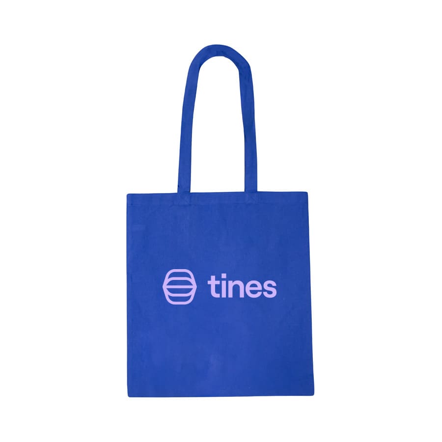 A vibrant blue cotton tote bag featuring a logo on one side. The bag has sturdy handles for easy carrying.