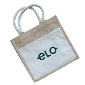 A jute tote bag featuring a natural beige colour with a white front pocket and a logo. The handles are white.