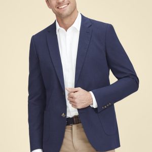 A man in a navy blazer over a white shirt, smiling against a neutral background. The blazer features a logo.