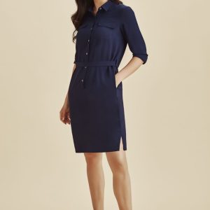 A navy blue shirt dress featuring a button-up front, belted waist, and side pockets, paired with white sneakers.