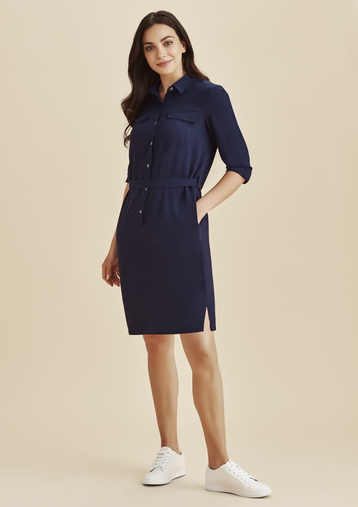 A navy blue shirt dress featuring a button-up front, belted waist, and side pockets, paired with white sneakers.