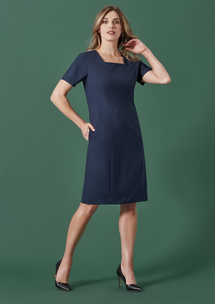 A women's short sleeve dress in black, featuring a fitted silhouette and pockets, displayed against a green background.