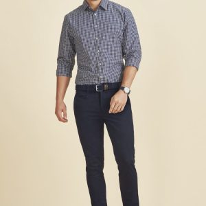 Men's tapered stretch chino pants in navy, paired with a checked shirt, featuring a belt and shoes.