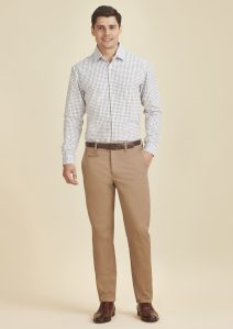 A man models modern stretch chino pants in a light tan colour, paired with a checked shirt. The outfit features a belt.
