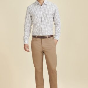 A man models modern stretch chino pants in a light tan colour, paired with a checked shirt. The outfit features a belt.