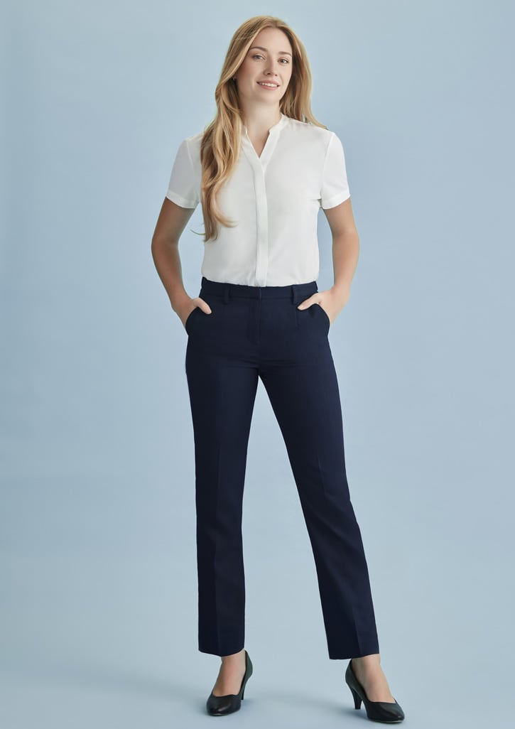 A woman models navy tapered leg pants with an adjustable waist, paired with a white blouse and heels, against a light blue background.