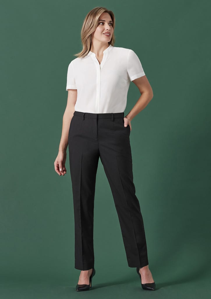 A woman wears black tapered adjustable waist pants with a white blouse against a green background. The image features a logo.