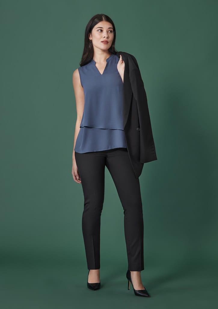 A woman stands wearing a sleeveless blue top and black slim leg pants, paired with a black blazer and heels.