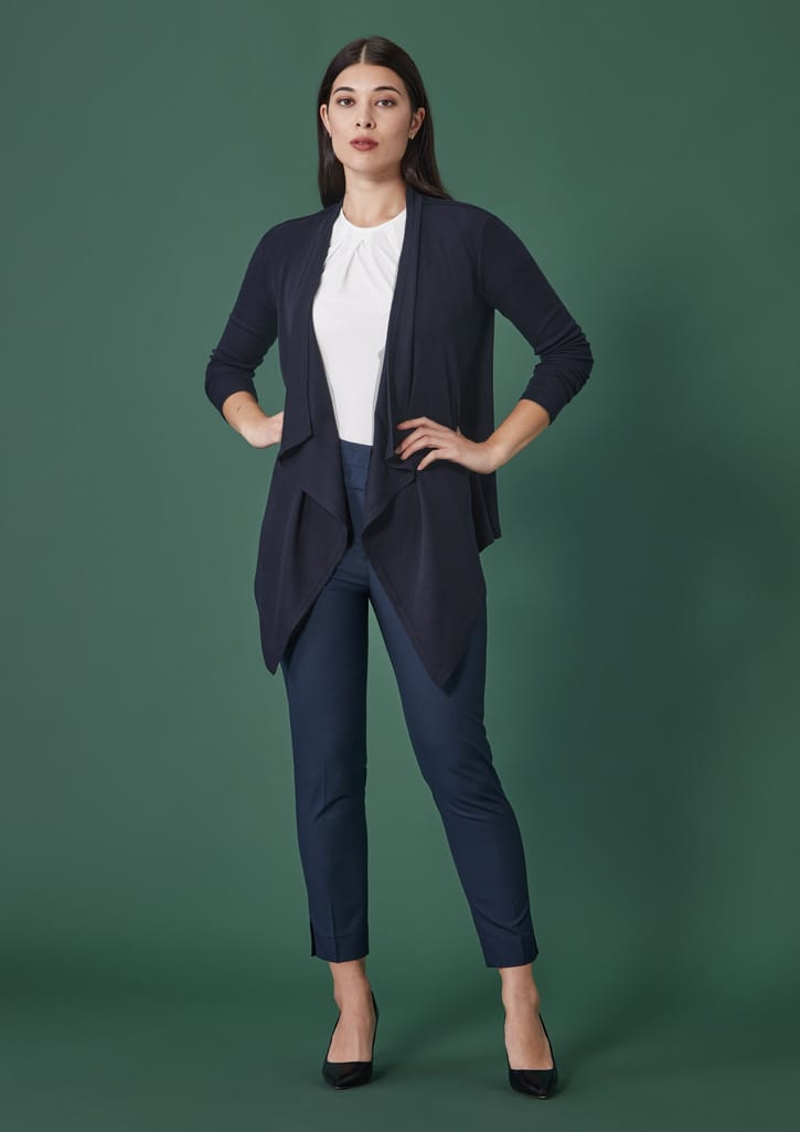 A model wearing navy mid-waist slim leg pants paired with a white top and a navy cardigan against a green background.