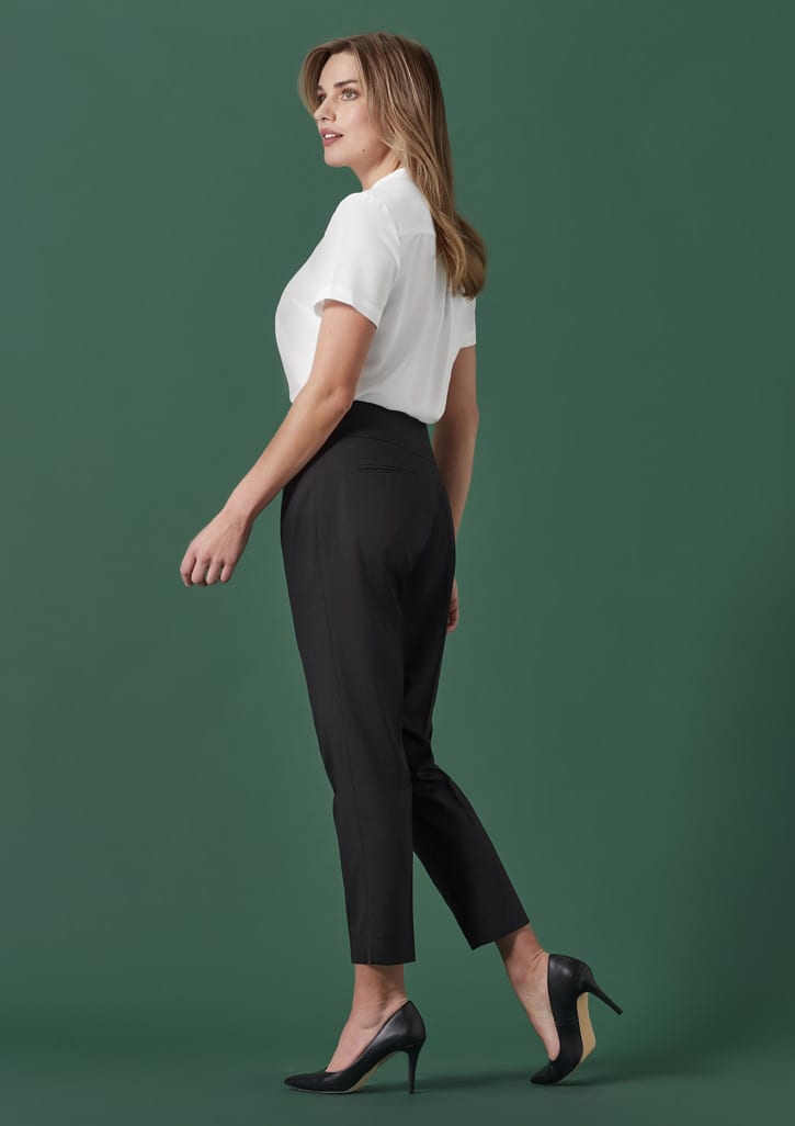 A woman models 7/8 mid-waist slim leg pants in black, paired with a white blouse and high heels.