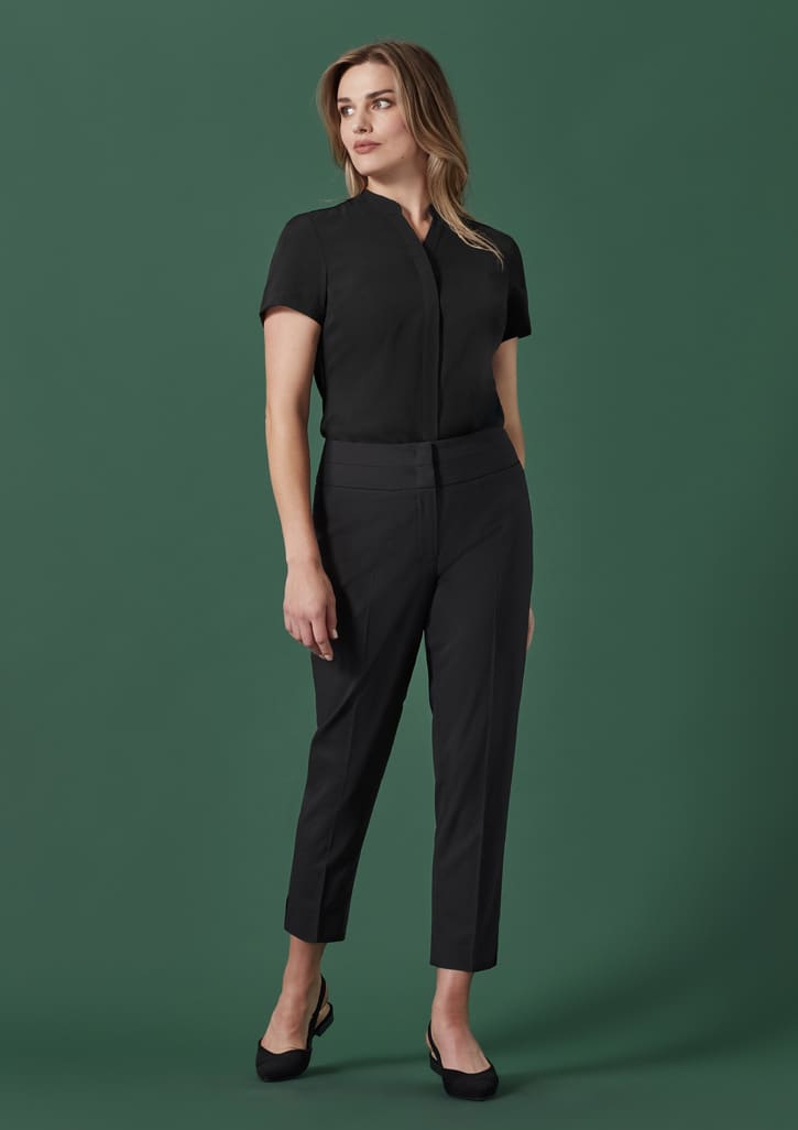Mid-waist slim leg pant in black, paired with a short-sleeved top, set against a green background.
