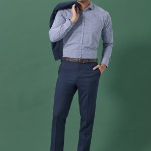 A pair of navy slim fit flat front pants displayed on a male model wearing a checked shirt and holding a blazer.