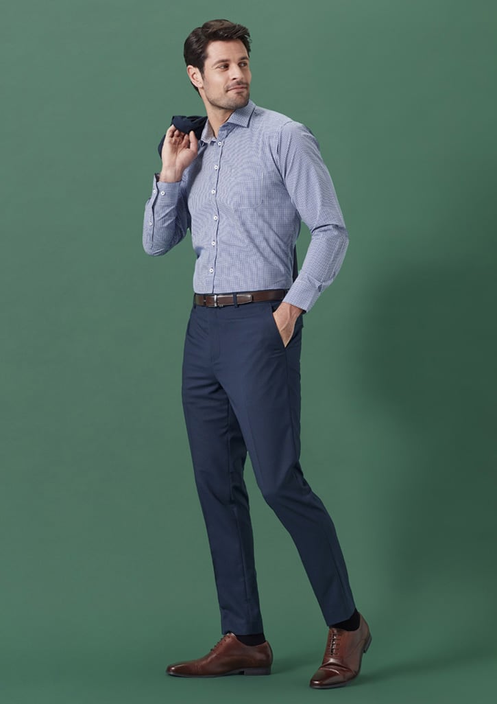 A man wearing a blue and white check shirt and navy slim fit flat front pants, holding a folded piece of fabric.
