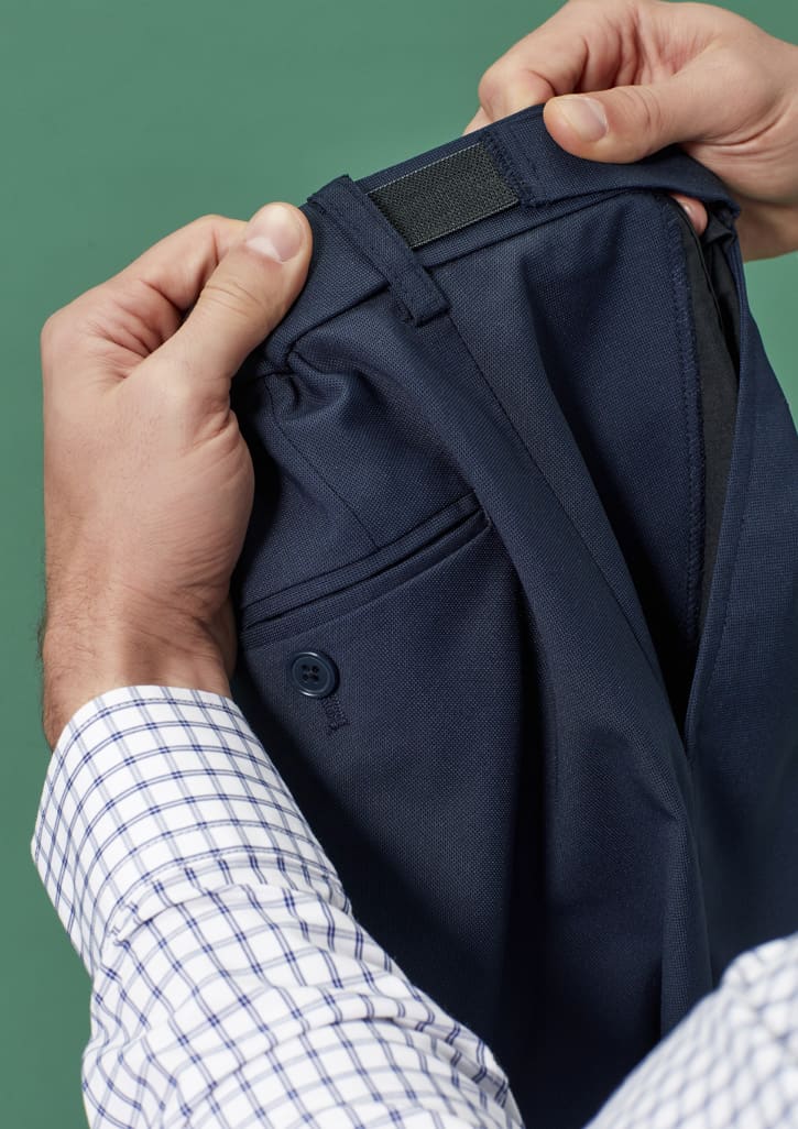 A person holding navy blue straight leg pants featuring an adjustable waist and a logo on the waistband.