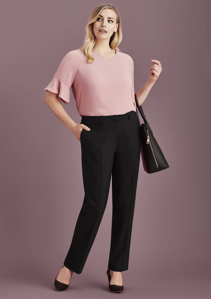 A pair of black slacks with a tailored fit, worn by a model with a pink top and holding a black handbag.