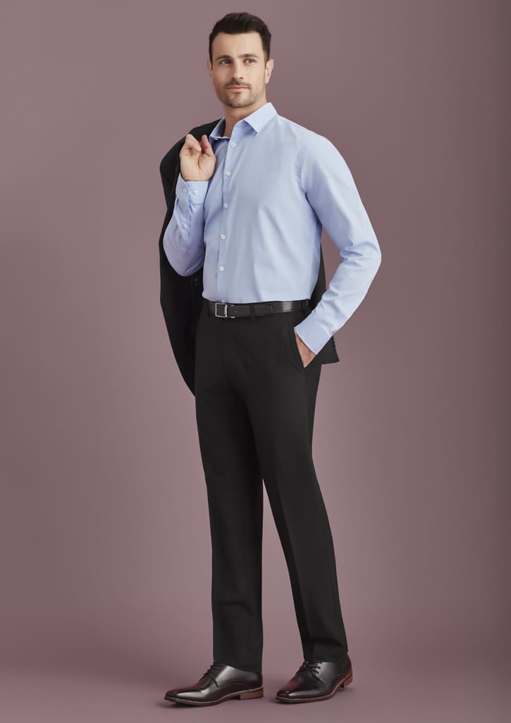 A man in a light blue shirt and black slacks, holding a black jacket on his shoulder. The slacks have a logo.
